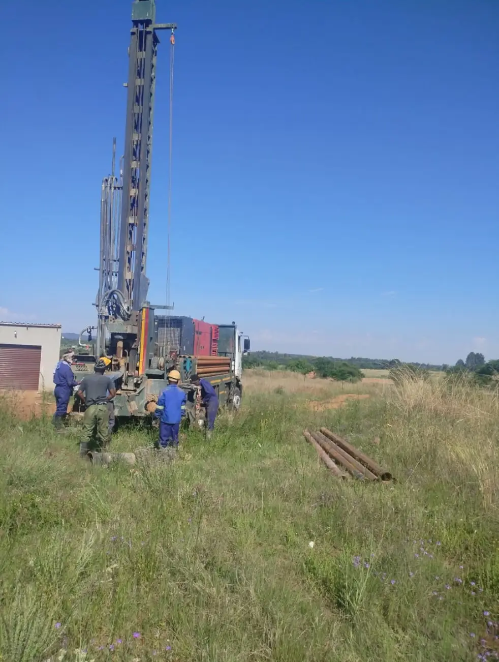 Suffix Boreholes teamin a field next to a borehole drilling rig and truck
